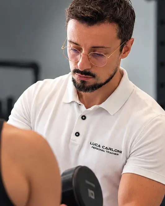 Luca Carloni segue da vicino un cliente durante un esercizio con il manubrio, nel suo studio a Legnano